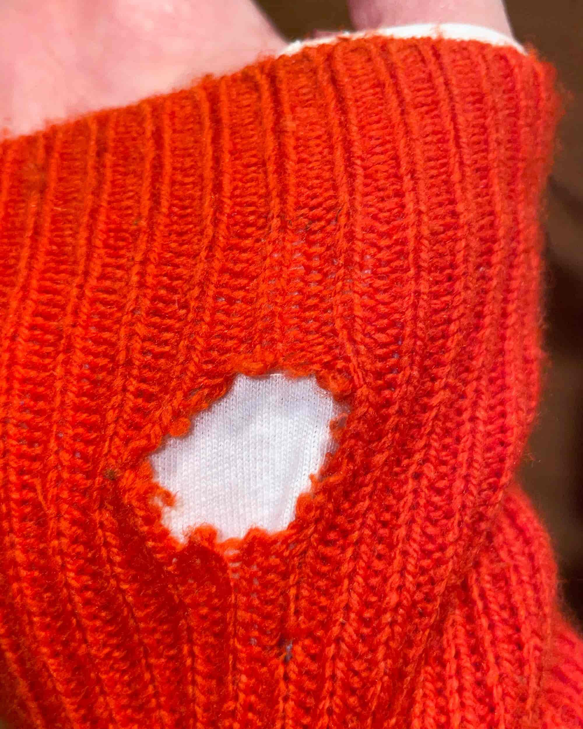 Close-up of a knitted sleeve with a visible hole before upcycling process.