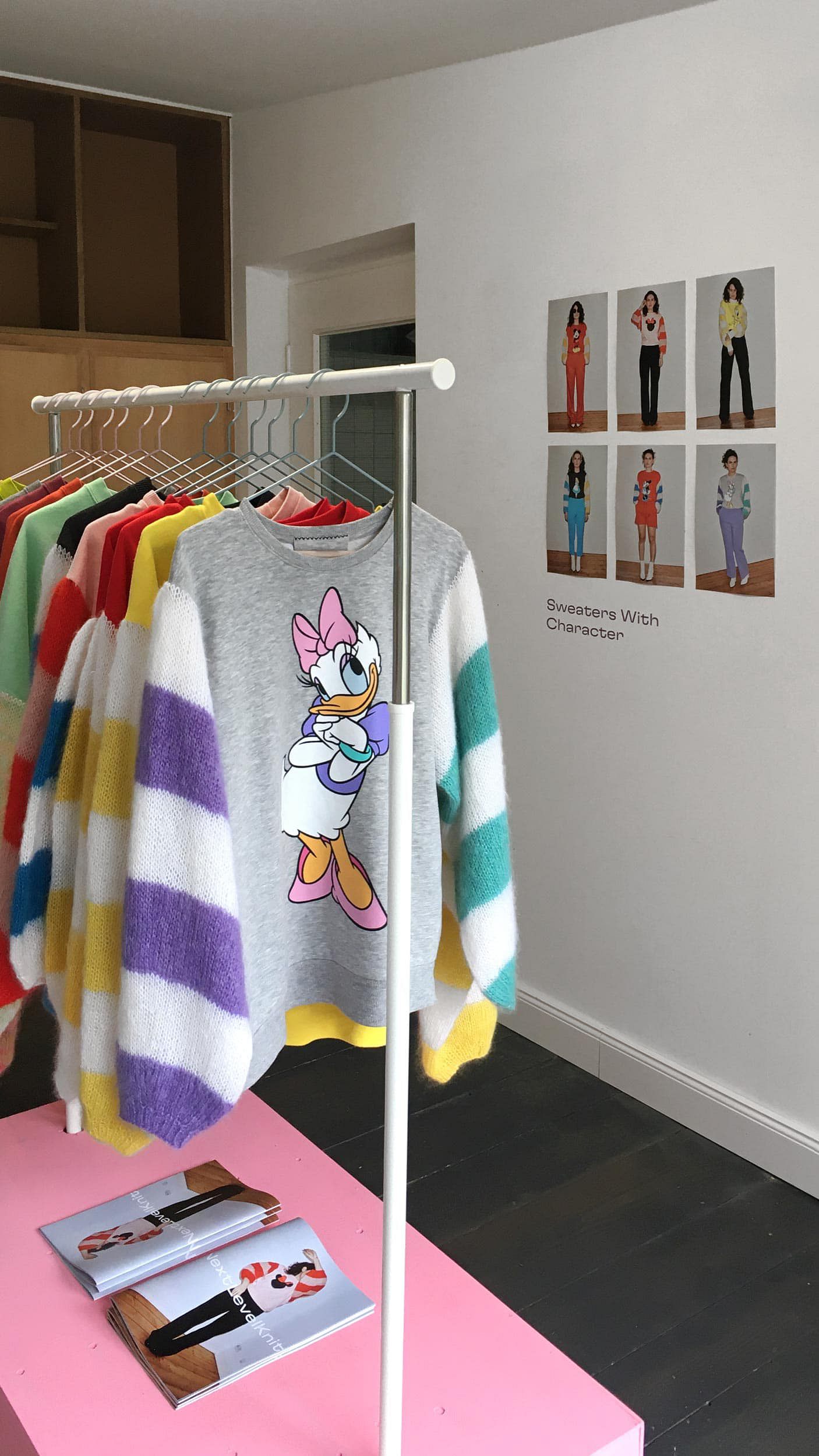 Several second-hand sweaters with hand-knitted sleeves, hanging neatly on a rack.