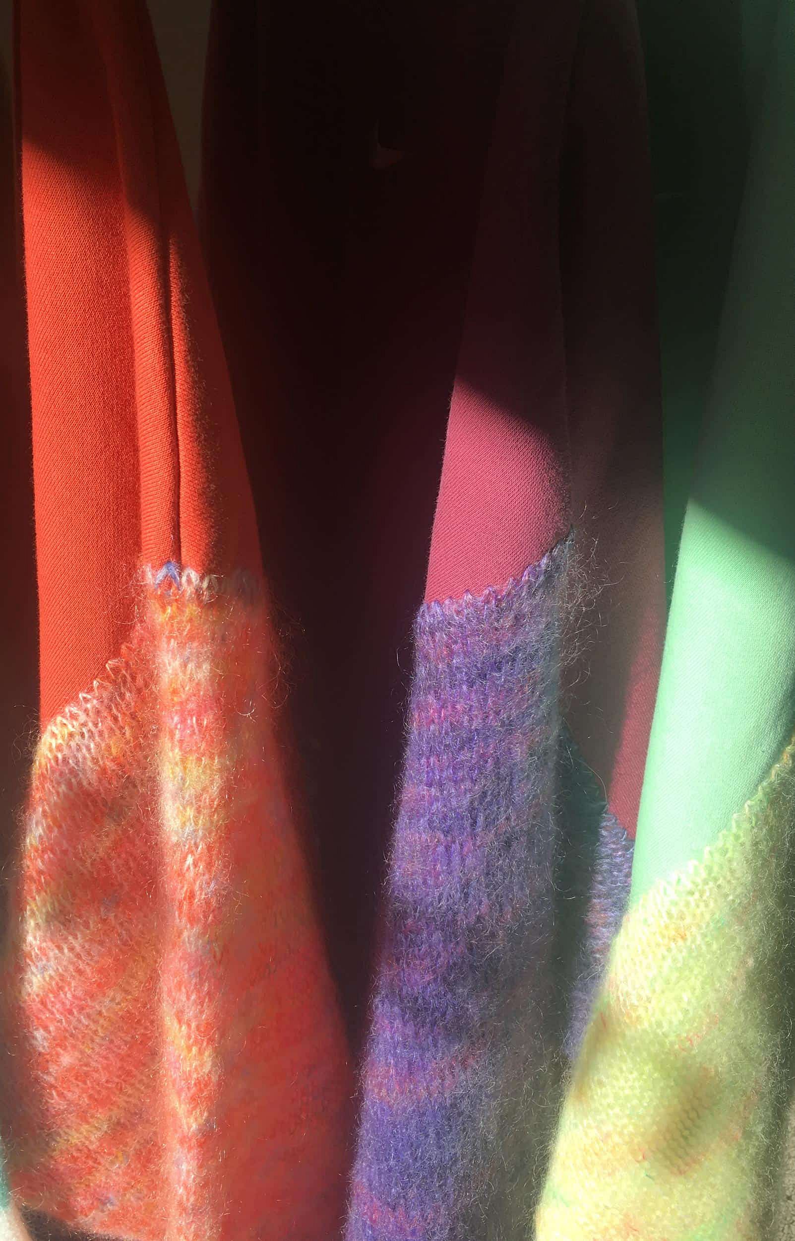 Close-up of stacked second-hand clothing in various colours, ready for sorting and customisation.